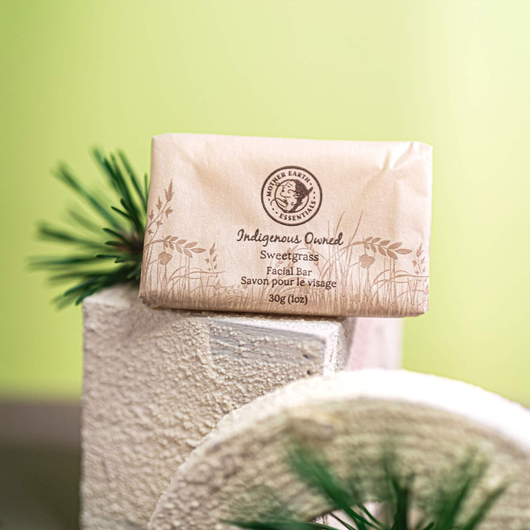 Facial sweet-grass soap bar with packaging on a white surface against a green background