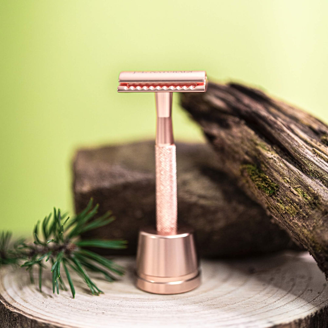J&L Naturals Stainless safety steel razor rose gold color on a wooden surface with a natural background