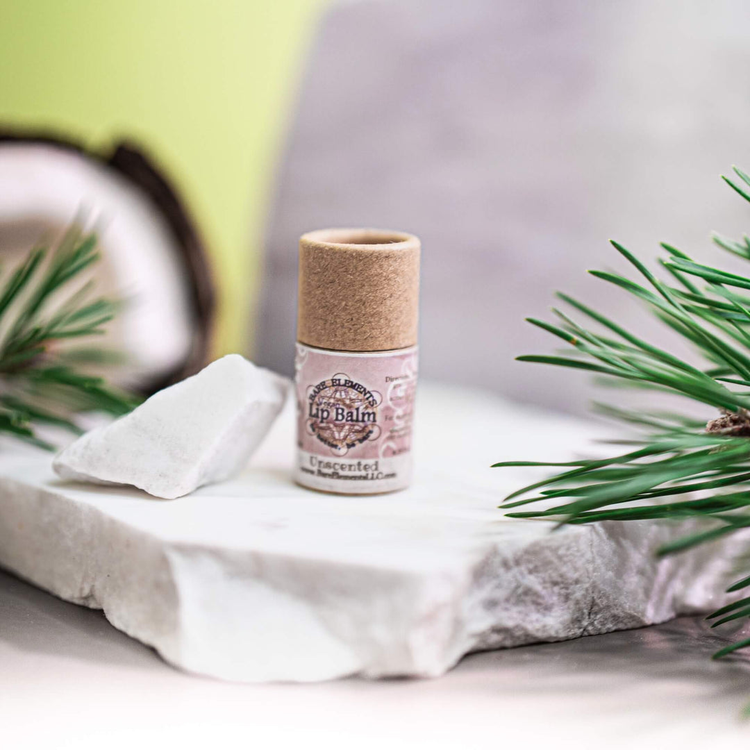 Lip balm on a white surface with greenery in the background