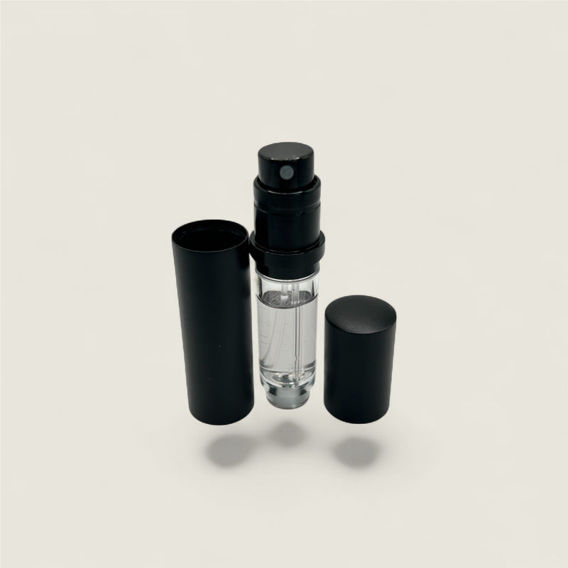Black perfume atomizer bottle with clear nozzle on a light gray background