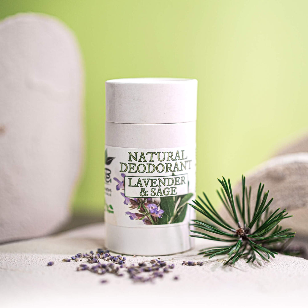 Natural deodorant stick with lavender and sage ingredients on a light surface with green background