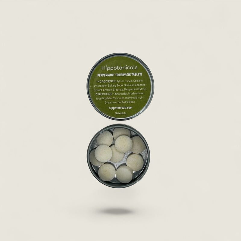 Hippotanics peppermint toothpaste tablets in a container on a beige background